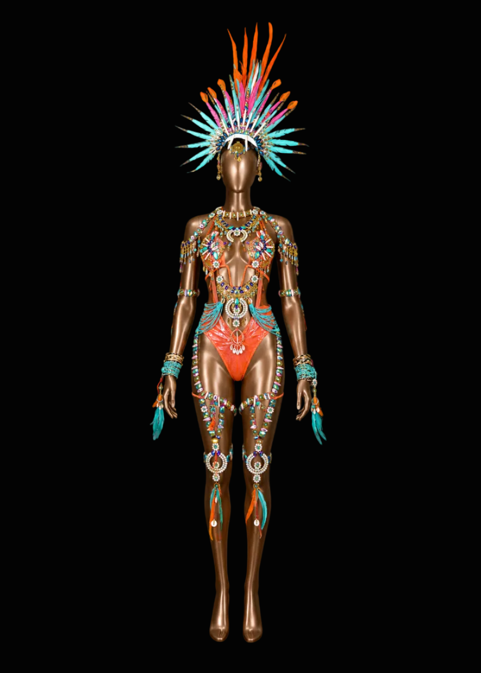 A metallic bronze mannequin wearing an elaborate, highly decorative body of jewelry and a matching feathered headdress. The adornment features bright turquoise, orange, gold, and silver elements, set against a solid black background.