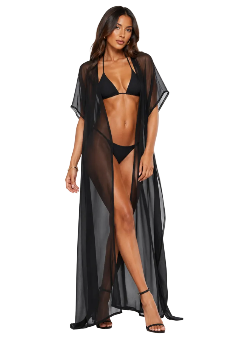 A woman modeling a sheer black maxi cover-up over a black bikini against a plain light gray studio background.