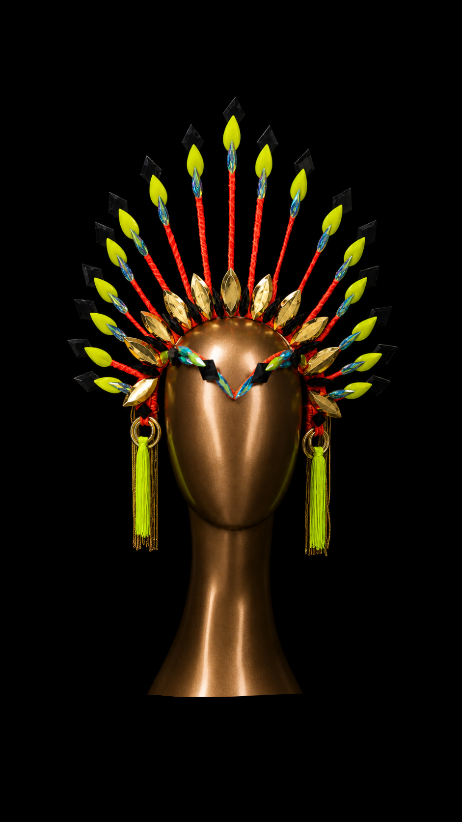 A vibrant, multi-colored feathered headdress displayed on a metallic bronze mannequin head against a solid black background.